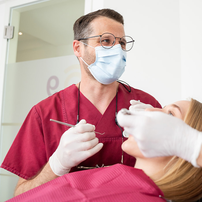 Dr. Feldmann mit Mundschutz während der Behandlung einer Patientin. 