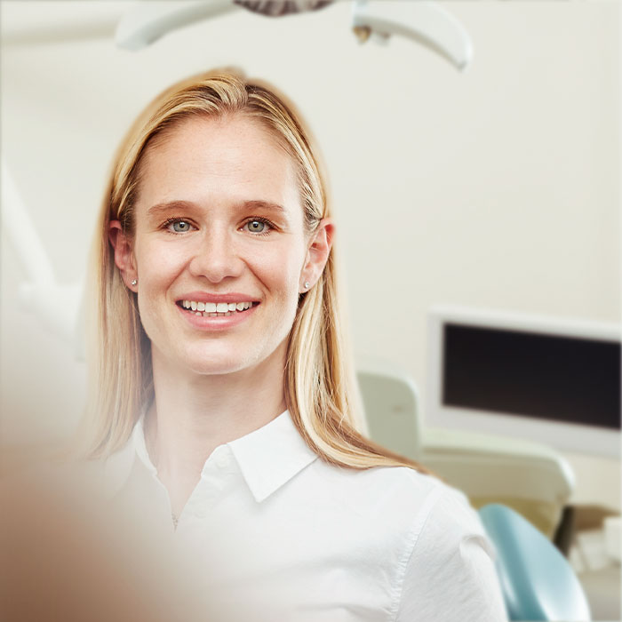 Dr. Klug mit Mundschutz und Lupenbrille während der Behandlung eines Patienten. 